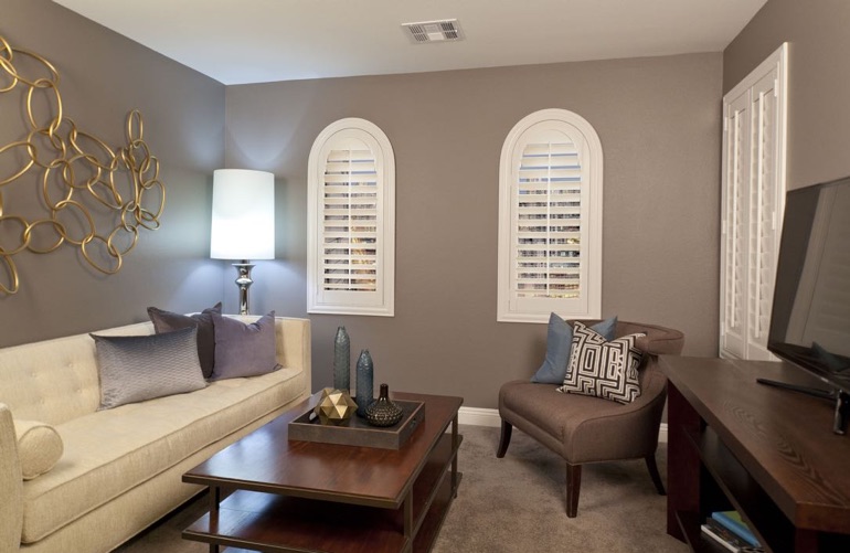 Plantation shutters on arched windows in neutral colored family room